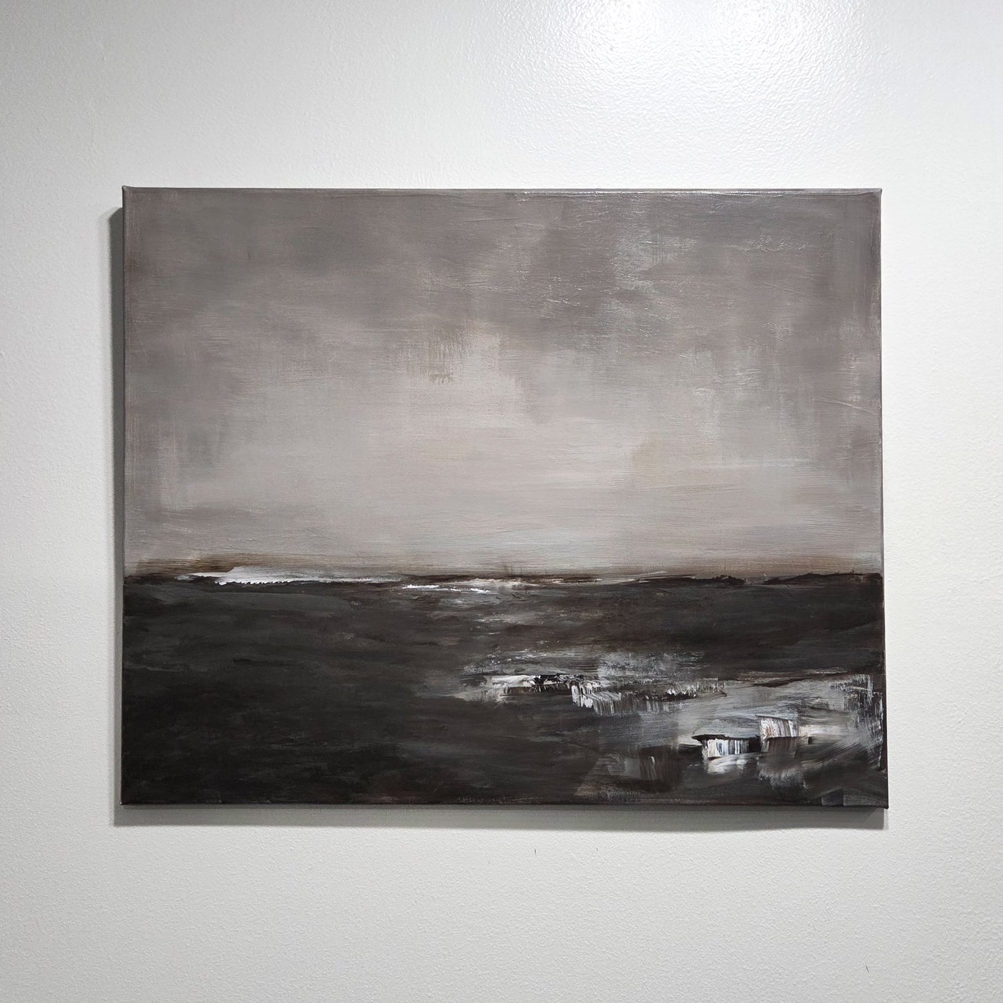 Abstract landscape painting with gray and black tones on a white wall